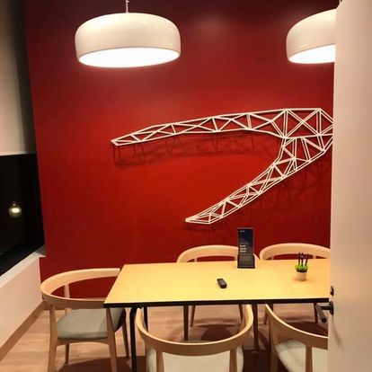 A room with a table and chairs in front of a red wall.