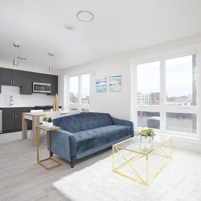 A living room with a blue couch and a glass coffee table.