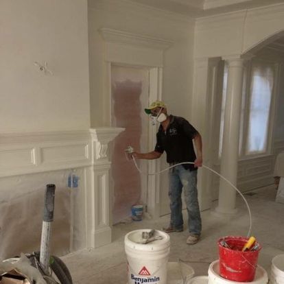 A man is spraying paint on a wall in a room.