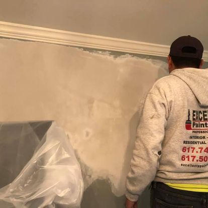 A man in a hoodie is painting a wall.