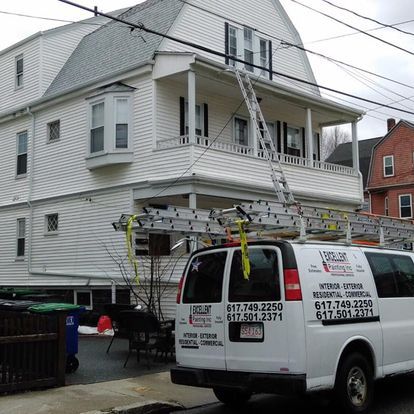 A white van is parked in front of a large white house