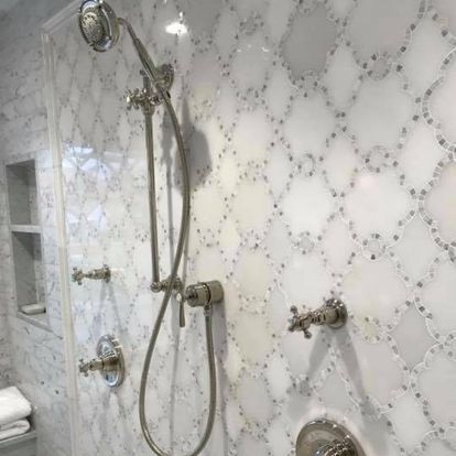 A bathroom with a shower head and faucets on the wall.