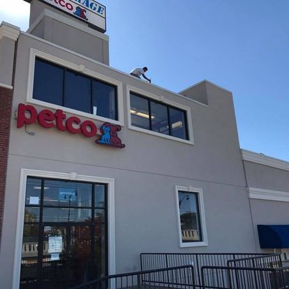 A man is working on the roof of a petco store