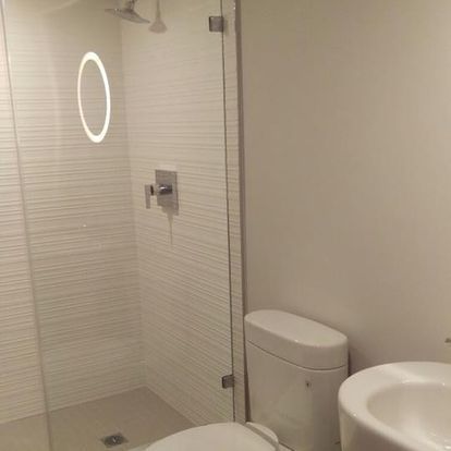 A bathroom with a toilet, sink and shower with a glass door.