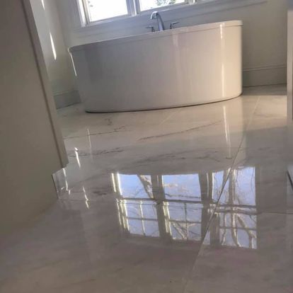 A white bathtub is sitting on a tiled floor in a bathroom.