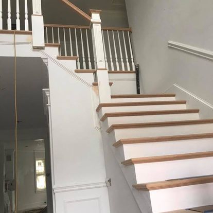 A white staircase with wooden steps and railing in a house.
