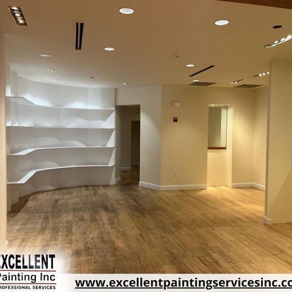 An empty room with hardwood floors and white shelves.