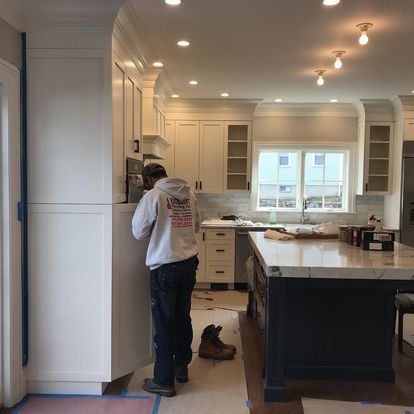 A man is standing in a kitchen with white cabinets and a large island.