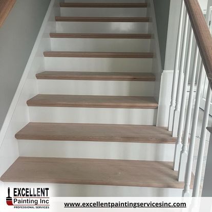 A staircase with wooden steps and white railing by excellent painting inc.