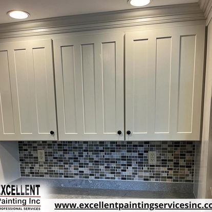 A kitchen with white cabinets and a tile wall.