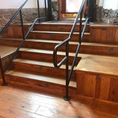 A set of wooden stairs with a metal railing in a building.