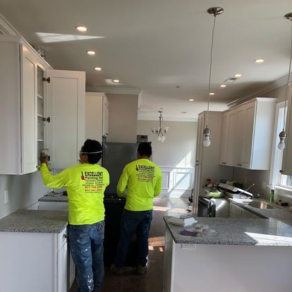 Two men in neon yellow shirts are working in a kitchen.