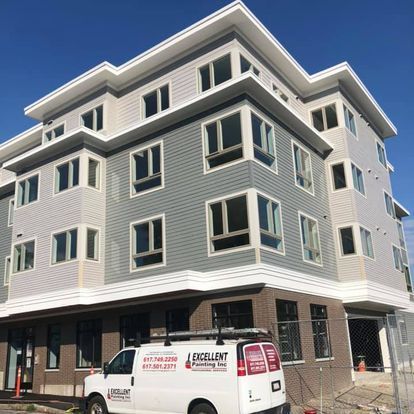 A white van is parked in front of a large building.