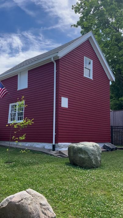 A red house with a white trim and an american flag on the side.