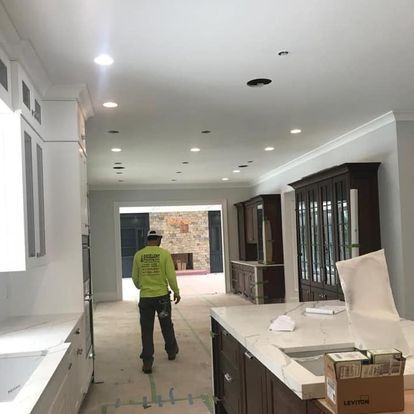 A man in a green shirt is standing in a kitchen.