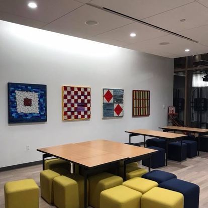 A room with tables and ottomans and paintings on the wall