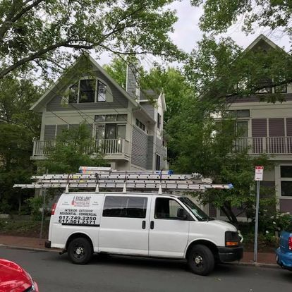 A white van with a ladder on top of it is parked in front of a house.