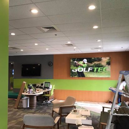 A room with a picture on the wall that says golftec
