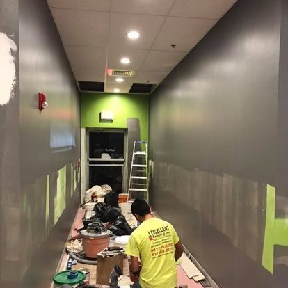 A man in a yellow shirt is painting a hallway.