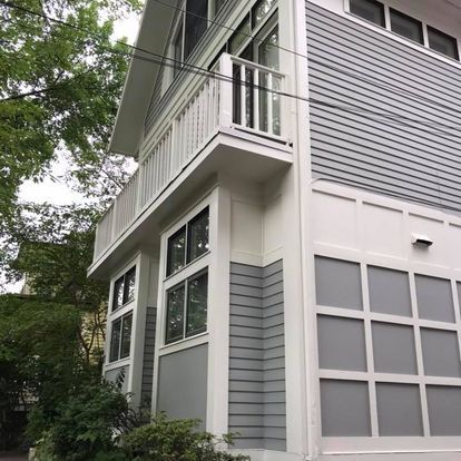 The side of a house with a balcony and a garage door.