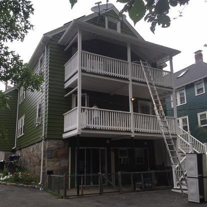 A green house with white balconies and stairs