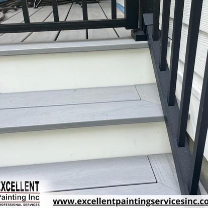 A close up of a set of stairs with a black railing.