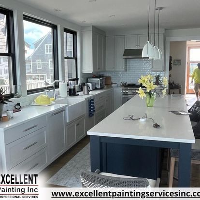 A kitchen with white cabinets, a large island, and a sink.