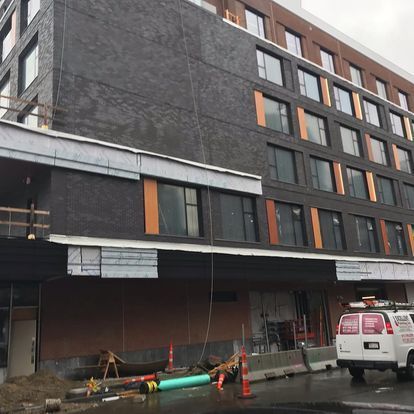 A large building under construction with a van parked in front of it.