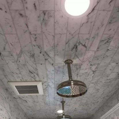 A shower head is hanging from the ceiling of a bathroom.