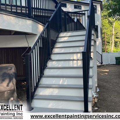 A set of stairs leading up to a house with a black railing.