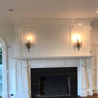 A living room with a fireplace and two lights on the wall.