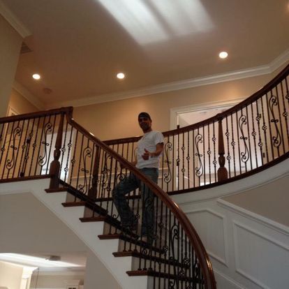 A man is standing on a curved staircase with a wrought iron railing