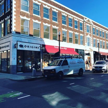 A white van is parked in front of a store called origins