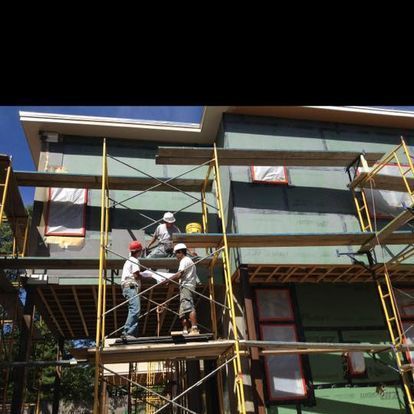A group of construction workers are working on the side of a building