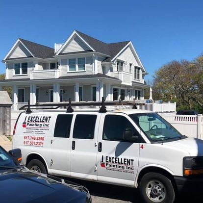 A white van is parked in front of a large white house.