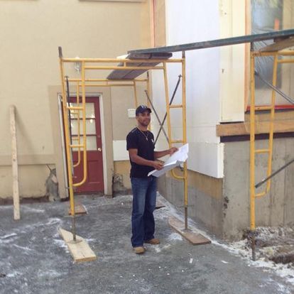A man is standing in front of a building holding a blueprint