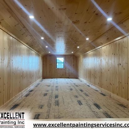 An empty room with wood paneling and a window.