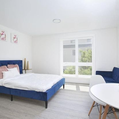 A bedroom with a bed, couch, table and chairs.