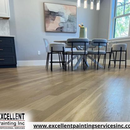 A dining room with a table and chairs and a painting on the wall.