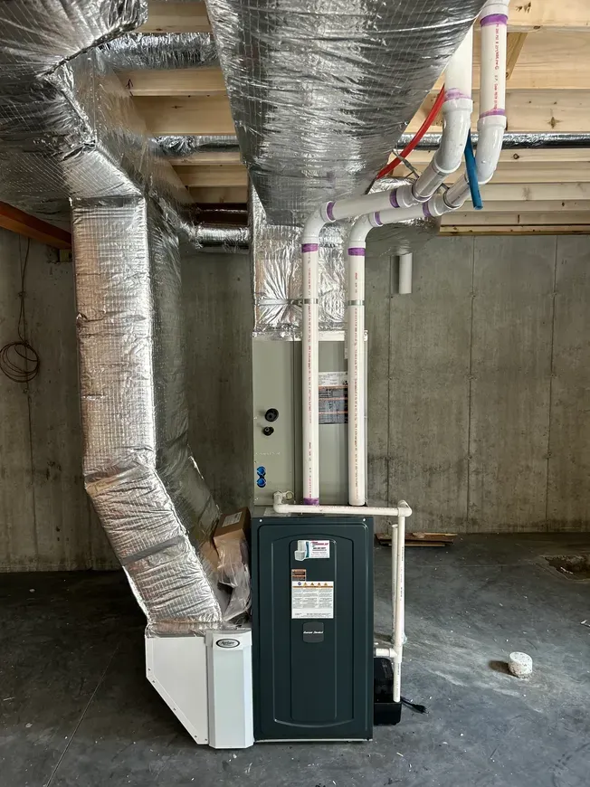 Basement mechanical room with HVAC ducts, furnace, and exposed concrete walls.