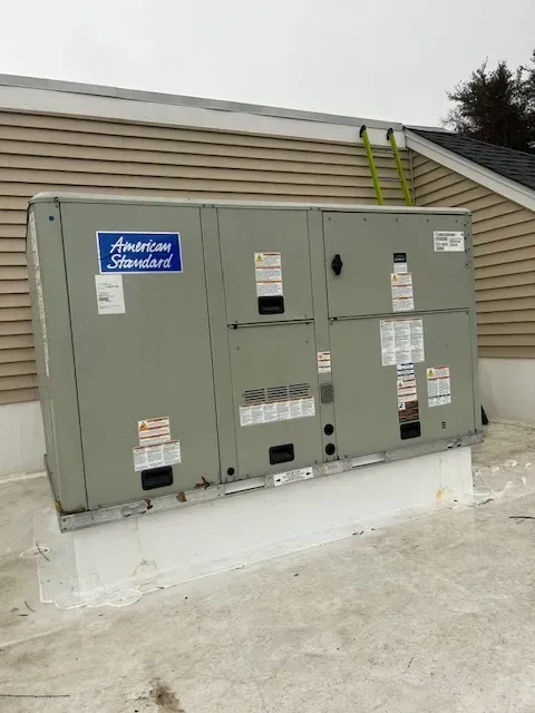 Outdoor HVAC units on a rooftop, with a yellow ladder against the building wall.