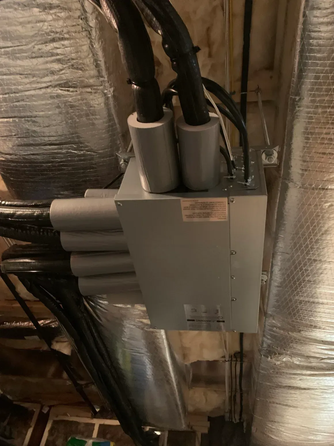 Electrical junction box with conduit and insulated HVAC ducts in a utility ceiling area