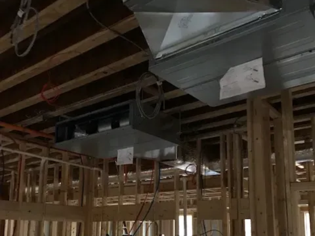 Exposed ceiling ductwork and wooden framing at a construction site under renovation