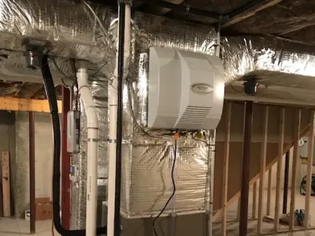 Basement with insulated ductwork and a white mounted HVAC unit on the wall.