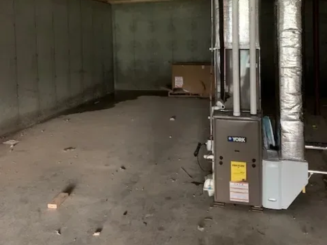 Empty industrial room with concrete floor and HVAC equipment on the right