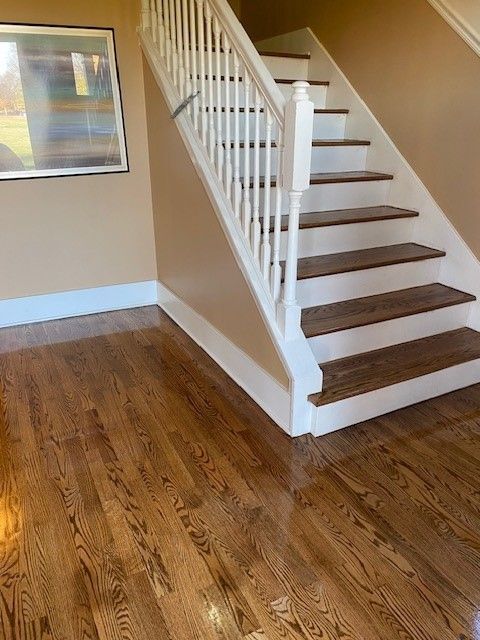 a staircase with wooden steps and a white railing in a room with hardwood floors