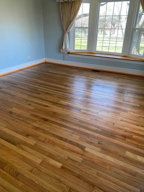 a living room with hardwood floors and two windows 