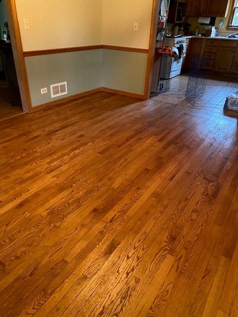 a living room with hardwood floors and a kitchen in the background