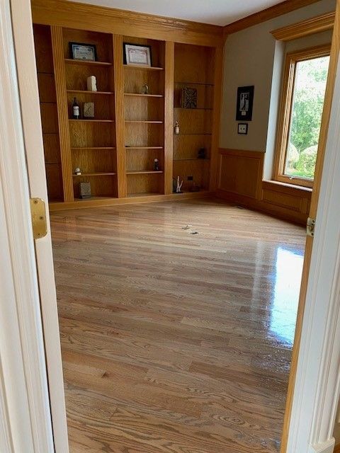 an empty room with hardwood floors and shelves