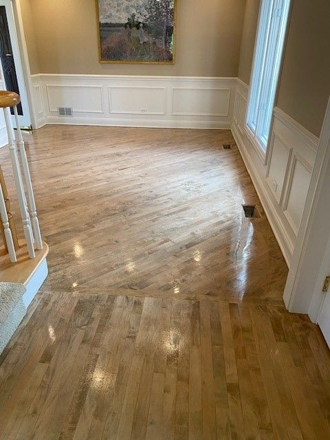 a living room with hardwood floors and stairs and a painting on the wall